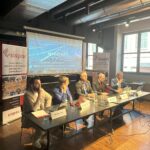 Relatori seduti al tavolo durante una discussione sull’impatto della NIS2 su aziende pubbliche e private.